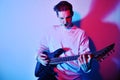 A man plays the electric guitar in neon light, red blue light. Hobbies, music, club. A man enjoys playing the guitar, screaming, Royalty Free Stock Photo