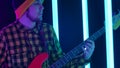 The man plays the guitar. Close up of the hand of a guitarist's fingering strings in neon lighting. Camera movement from