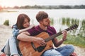 Man plays guitar for his girlfriend at beach on their picnic at daytime Royalty Free Stock Photo