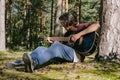 A man plays the guitar while sitting in the forest near a tree. Against the backdrop of nature Royalty Free Stock Photo