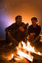 Man plays guitar and woman about the fire on the background of the starry sky Royalty Free Stock Photo