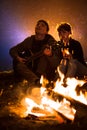 Man plays guitar and woman about the fire on the background of the starry sky Royalty Free Stock Photo