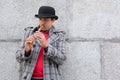 A man plays a musical instrument sopilka on the street against the background of the wall