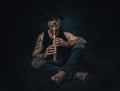 Man plays a native american flute in a studio, atelier photos, black background. Royalty Free Stock Photo