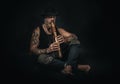 Man plays a native american flute in a studio, atelier photos, black background. Royalty Free Stock Photo