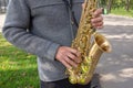Man plays on saxophone in the park. Street musician with sax performs music for charity. Public solo performance by wind Royalty Free Stock Photo