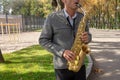 Man plays on saxophone in the park. Street musician with sax performs music for charity. Public solo performance by wind Royalty Free Stock Photo