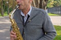 Man plays on saxophone in the park. Street musician with sax performs music for charity. Public solo performance by wind Royalty Free Stock Photo