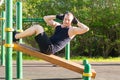 A man plays sports in the open air, listens to music, on a special platform, does an exercise on a press and looks into the camera