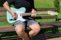 Man playing a turquoise electric guitar in a park on a sunny day Royalty Free Stock Photo