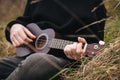 A man plays the ukulele guitar in nature, sitting on the grass. Royalty Free Stock Photo