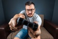 A man plays a video game console while sitting on a sofa. Day off, entertainment, leisure