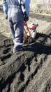 Man plows the ground with motor cultivator. Walk-behind tractor, motor-block in garden. Preparation for planting