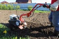 A man plows land for planting crops in his garden in a polisadnik, a private house with a garden, work in the garden, men`s work