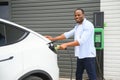 Man Plugging In Electric Car Outside Office In Car Park Charging