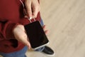 Man plugging headphones to smartphone indoors, closeup. Space for text Royalty Free Stock Photo