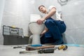 Man plumber in uniform repairing toilet bowl using instrument kit professional repair service Royalty Free Stock Photo