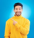 Man, point and smile in studio portrait with choice, fashion and promotion with excited face by blue background. Young