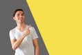 Man pointing away with finger standing against gray yellow background Royalty Free Stock Photo