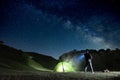 Man pointing blue flashlight to mountain below starry sky in Nebrodi Park