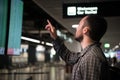 Man pointing with a finger at blur flight schedule for check timetable to departure at international airport terminal Royalty Free Stock Photo