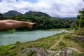 Man pointing finger on distant lake shore and forest. Natural tourism hiking concept photo. Treking path around summer lake