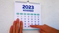 A beautiful November page of the wall calendar 2023 and a man points a finger at the marked Thanksgiving date