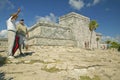 Man pointing in front of Mayan ruins of Ruinas de Tulum (Tulum Ruins) in Quintana Roo, Mexico. El Castillo is pictured in Mayan ru