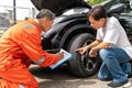 A man pointing out the damage on his car's tyre from the car accident to the car insurance mechanic