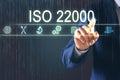 Man pointing at virtual screen with text ISO 22000 and different icons, closeup