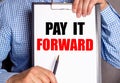 The man points with a pen to the text PAY IT FORWARD on a white sheet Royalty Free Stock Photo