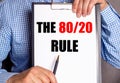 The man points with a pen to the text THE 80 20 RULE on a white sheet