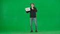 A man points to a placard in his hand that says go vegan. Male vegan demonstrator in studio on green screen full length.