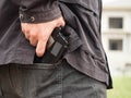 A man, policeman or robber, gangster concealing his gun behind his back