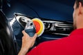 Man polishing car headlight with polish machine. restore vehicle lights Royalty Free Stock Photo