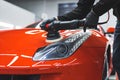 a man polishing an orange car headlight, indoors Royalty Free Stock Photo