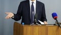 A man - a politician, businessman, official or lawyer gesticulates with his hands, speaking from the podium in front of