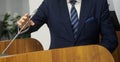 Man - politician, businessman or teacher is preparing to speak in front of a microphone on a podium or lectern. Official press