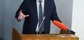 Man - politician, businessman or teacher speaks in front of microphones, leaning on podium or pulpit and gesticulating with his Royalty Free Stock Photo