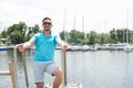 Bearded Man in polo and sunglasses laddering up on boat. Happy businessman on vacation with yachts on dock Royalty Free Stock Photo