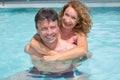 Man in the pool gives a piggy back to a woman Royalty Free Stock Photo