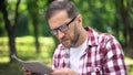 Man with poor sight trying to read newspaper in park, farsightedness, myopia Royalty Free Stock Photo