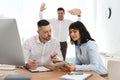 Man popping paper bag behind his colleagues. April fool`s day