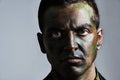 Man, portrait and camouflage with face paint for war, battle or military service on a gray studio background. Closeup of Royalty Free Stock Photo