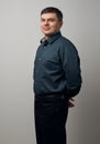 Man portrait with crossing hands, dressed in dark shirt and black pants over gray background Royalty Free Stock Photo