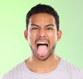 Man, portrait and frown in studio, tongue and goofy comic or funny face on green background. Male person, mockup space