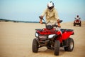 Man poses on atv, downhill riding in desert sands Royalty Free Stock Photo