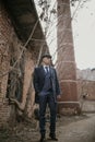 A man posing in the image of an English retro gangster dressed in Peaky blinders style near abandoned building