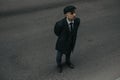 A man posing in the image of an English retro gangster in Peaky blinders style at city street