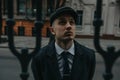 A man posing in the image of an English retro gangster in Peaky blinders style at city street